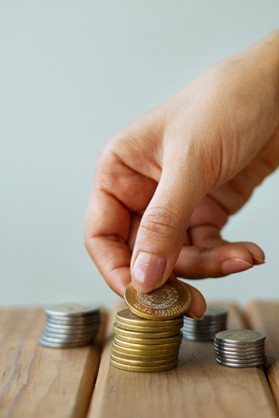 Mano sosteniendo monedas por sobrecostos en proyectos de construcción